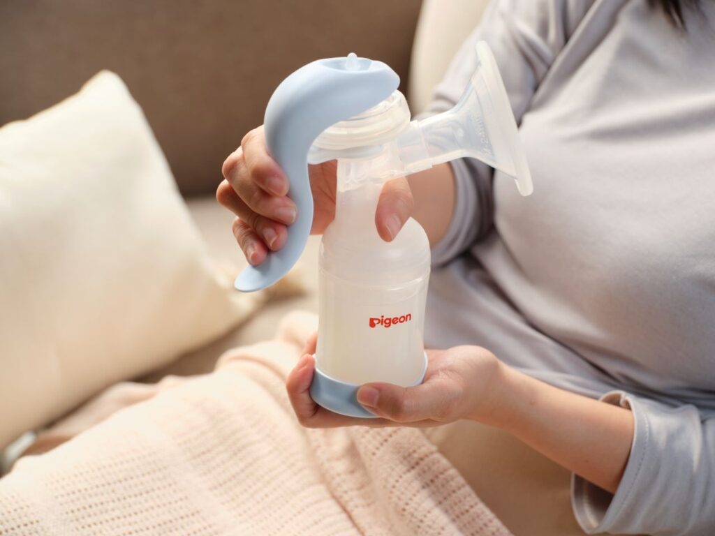 A mother using the Pigeon Manual Breast Pump for convenient milk expression, featuring adjustable suction and ergonomic design.