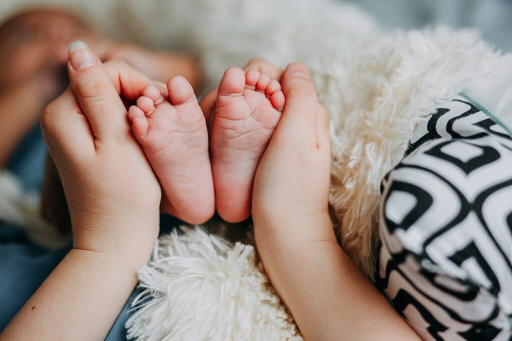 A mother gently holding her baby's tiny feet, symbolizing the importance of baby skincare and nourishment. Keep your baby’s skin soft with the best baby lotion in Malaysia.