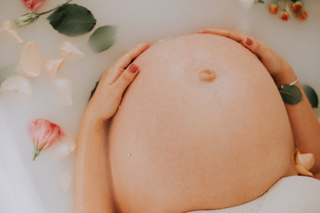 A pregnant woman relaxing in a milk bath, emphasizing self-care during pregnancy. Use the best stretch mark cream in Malaysia to keep skin hydrated and nourished.