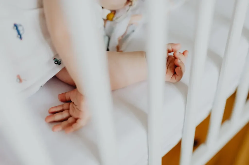 Baby lying in crib during night-time feeding routine with safe sleep setup