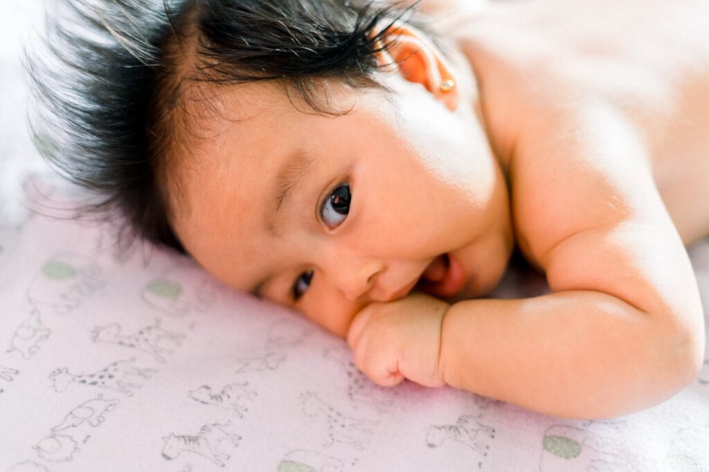 Happy baby lying on soft bedding, representing comfort and satisfaction from using the right bottle teat for smooth feeding.