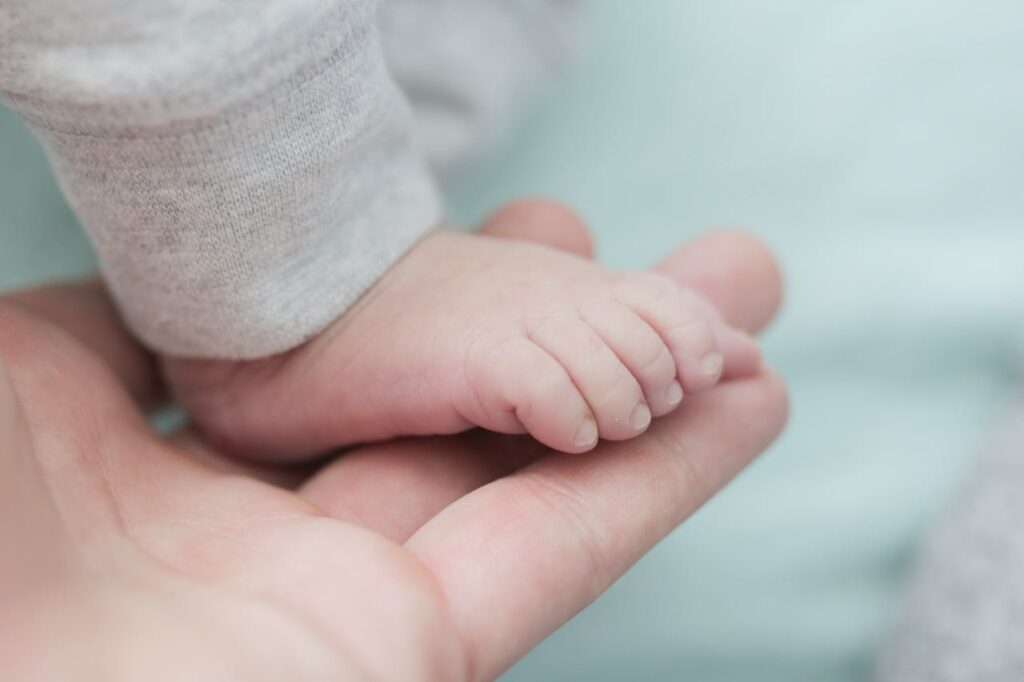 Parent gently holding a newborn baby’s tiny foot, symbolizing tender baby skin care and the importance of using gentle baby lotion.