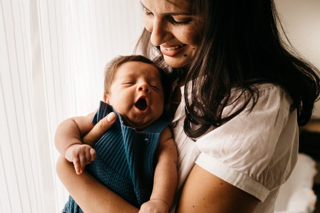 Mother holding newborn in an upright position to support burping after baby feeding.