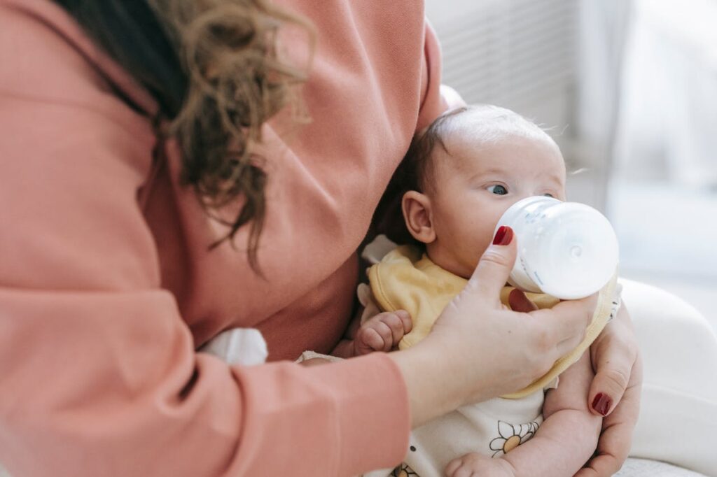 Parent bottle feeding the baby in semi upright position to reduce air intake.