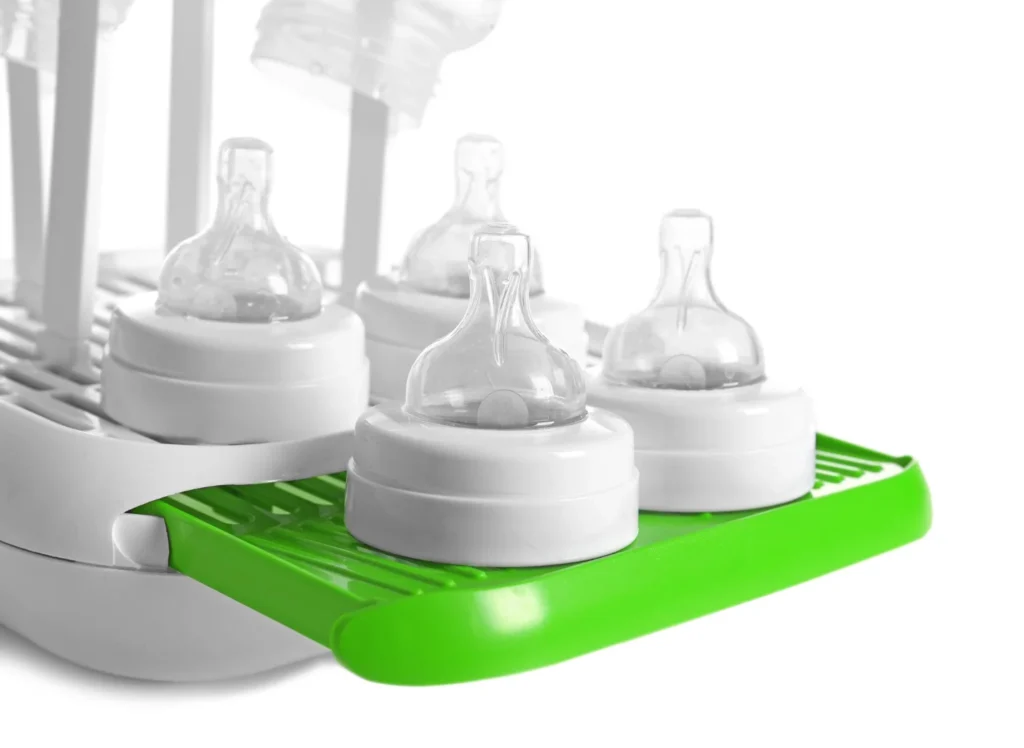 Sterilised baby bottles with teats drying upside down on a bottle drying rack
